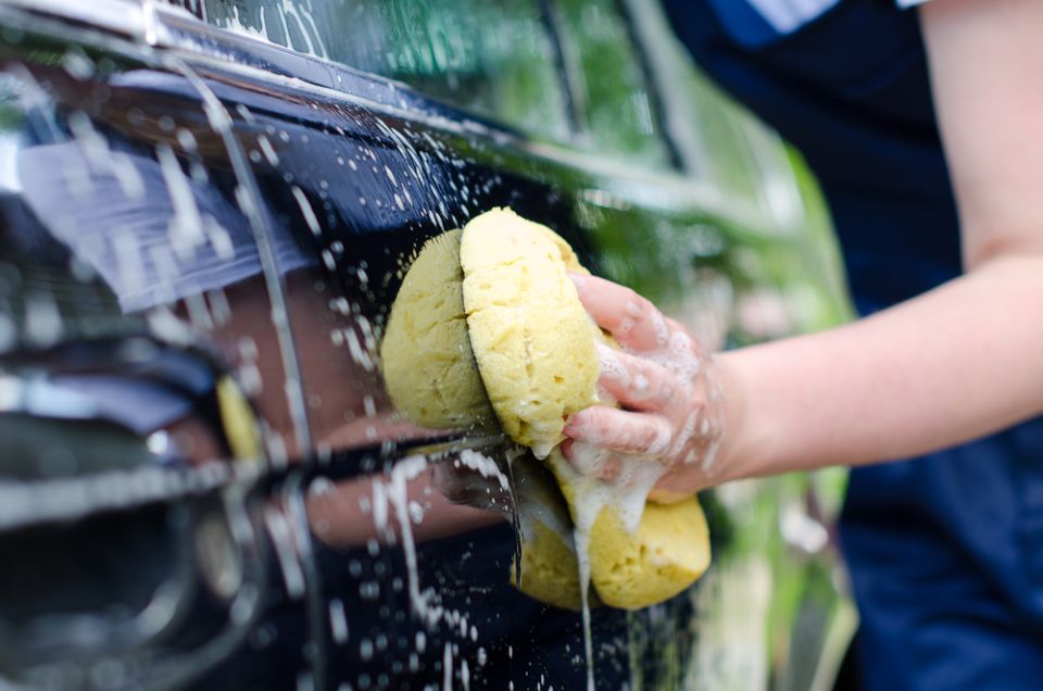 Työntekijä pesee autoa sienellä